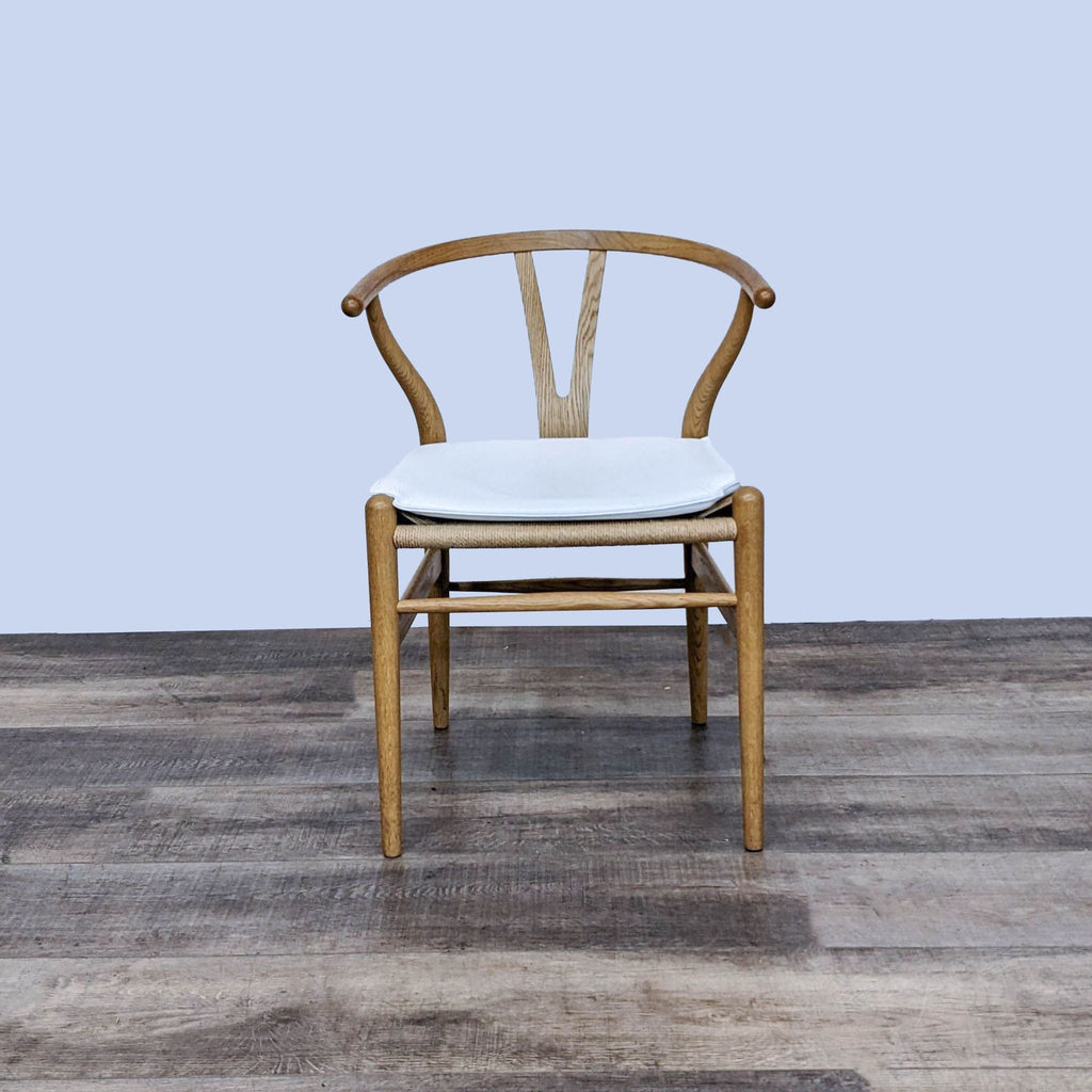 Wegner Wishbone Chair with white cushion, featuring a curved back and light wood design.