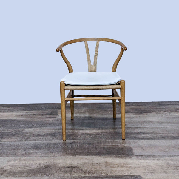 Wegner Wishbone Chair with white cushion, featuring a curved back and light wood design.