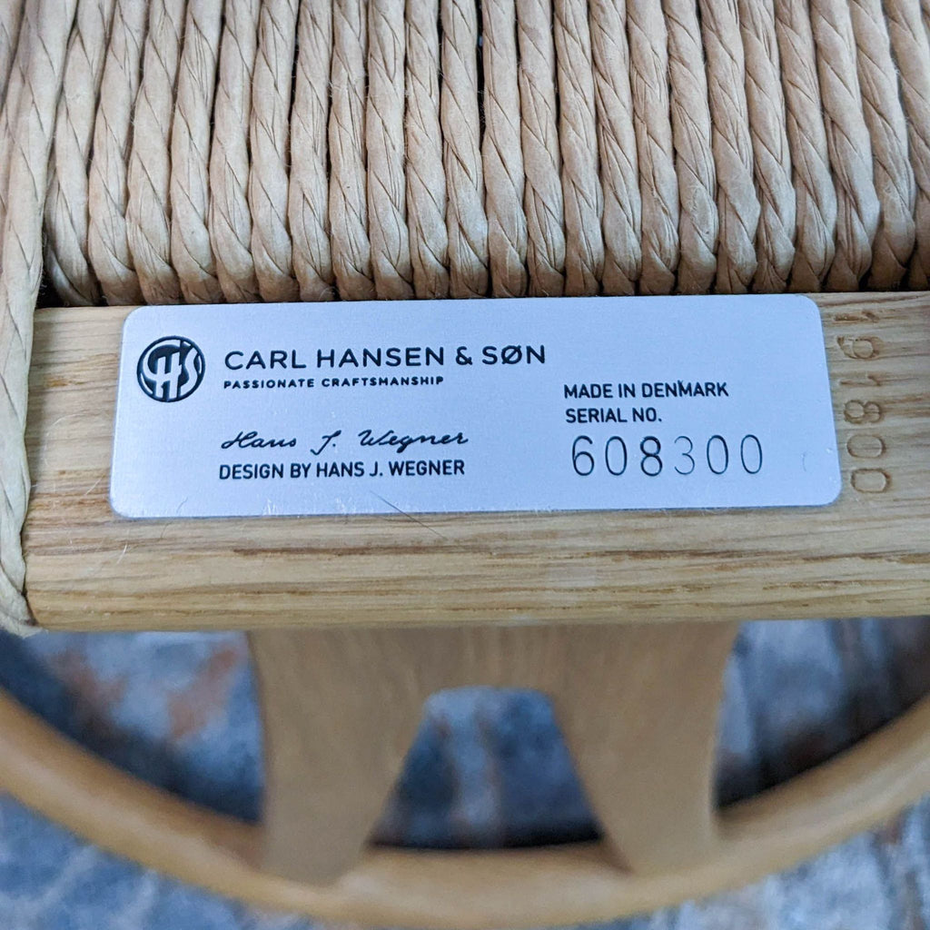 Close-up of Carl Hansen & Son label on the Wegner Wishbone Chair, showing serial and design details.