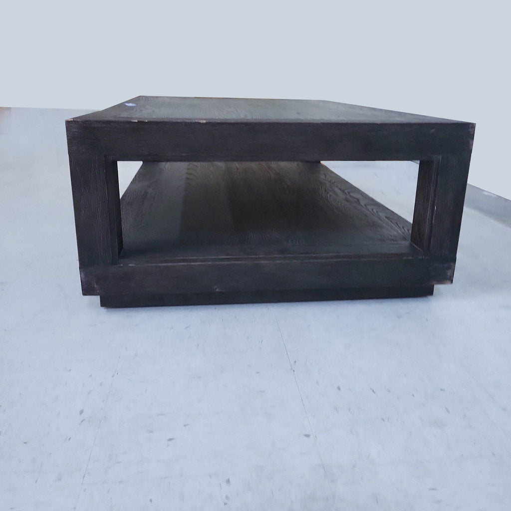 Side view of dark wood coffee table by Restoration Hardware featuring open rectangular design and lower shelf.