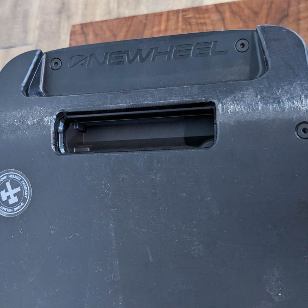 The underside of a black Onewheel, displaying brand engraving and wear marks.