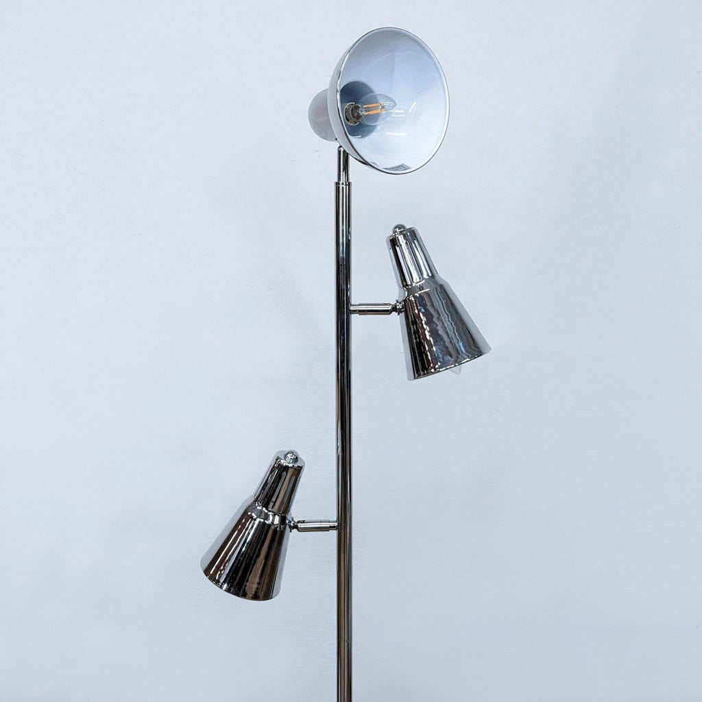 Close-up of a floor lamp's reflective chrome spotlights on a slim metal pole.
