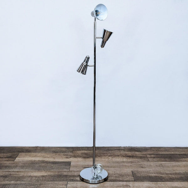 Sleek floor lamp with three adjustable chrome spotlight heads on a wooden floor.