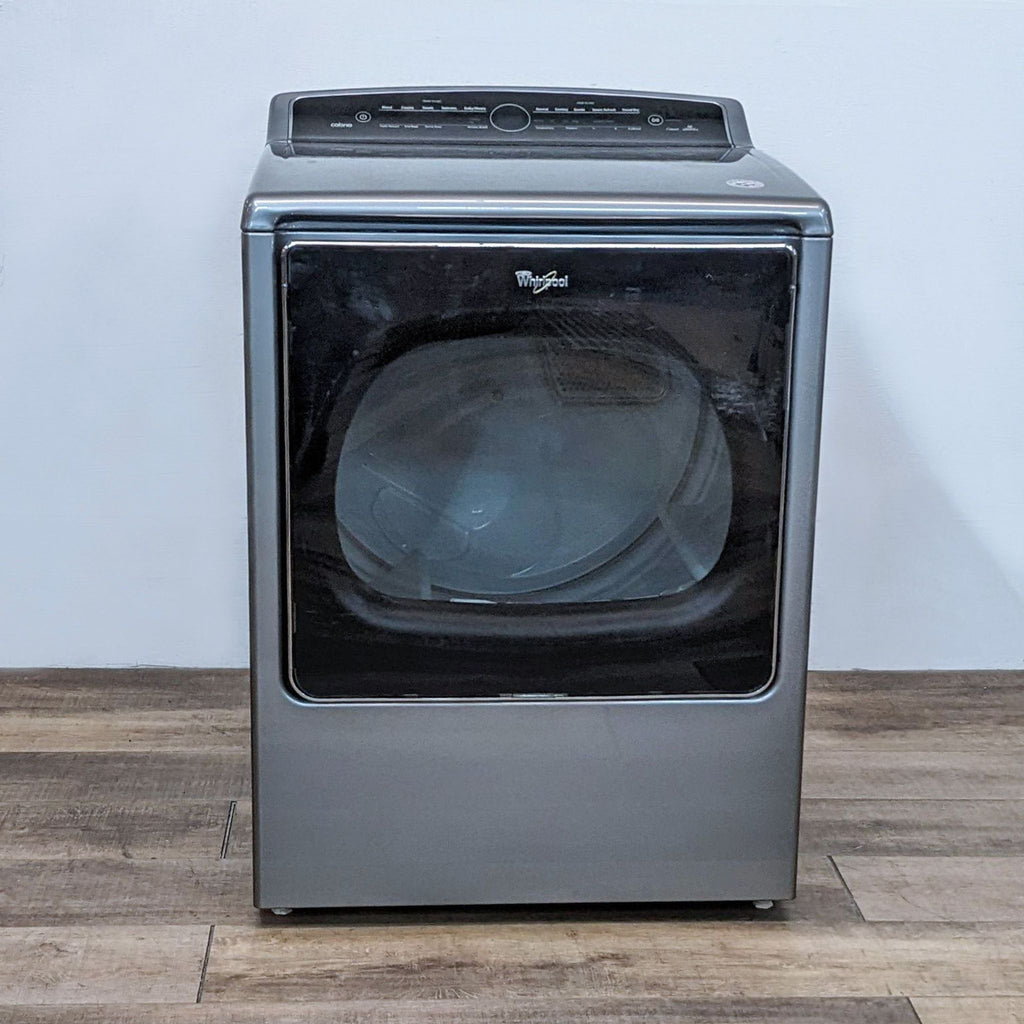 Front view of a Whirlpool washer/dryer in metallic finish, featuring a large glass door and digital controls.