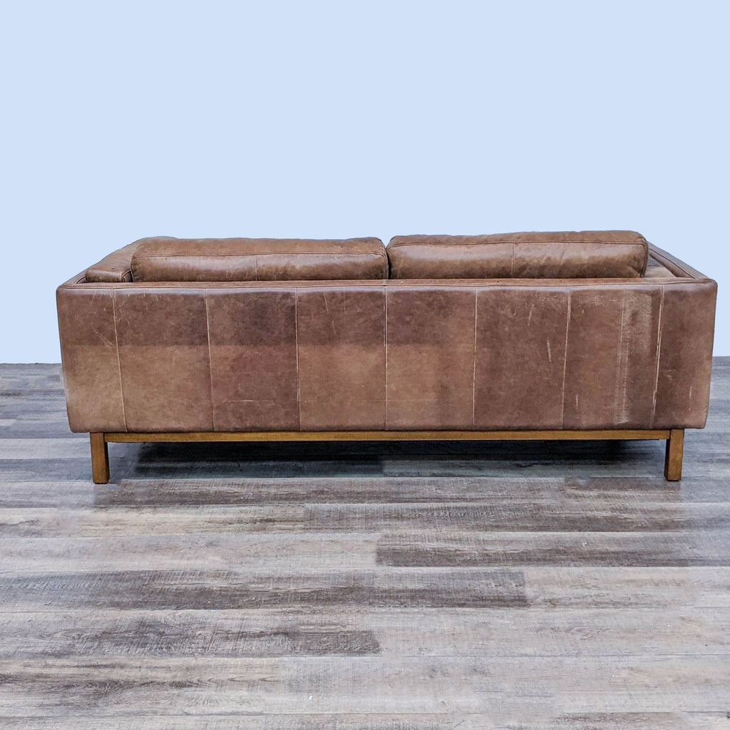Back view of a saddle-colored leather sofa with a hardwood frame.