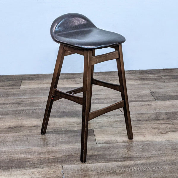 Leather-look brown stool with solid wood frame, brand Reperch, on wooden floor.
