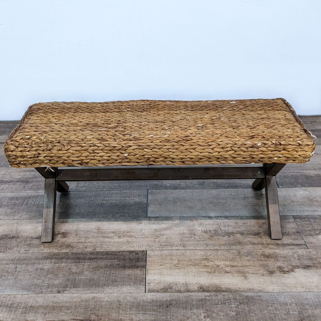 Woven reed bench by Reperch with criss-cross wooden legs.