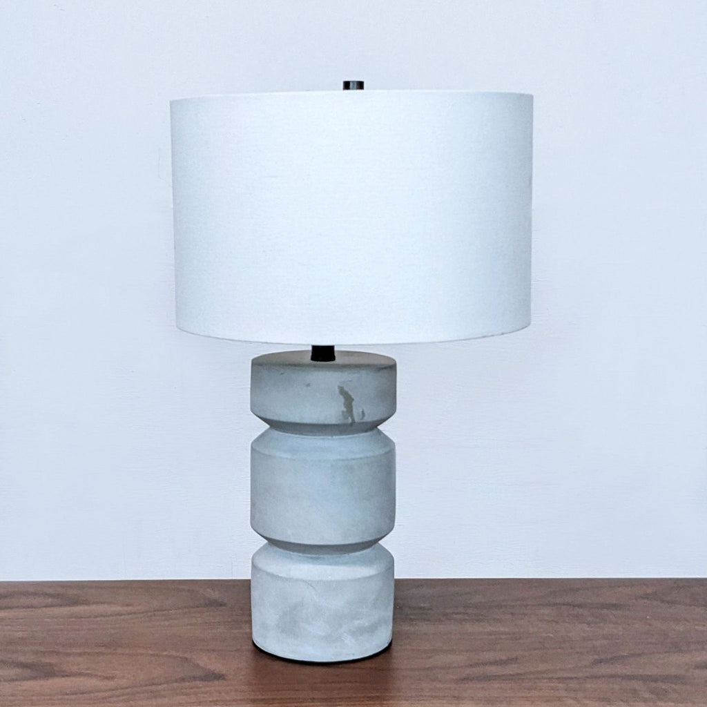Reperch lamp with a minimalist design featuring a cylindrical white shade and gray base.