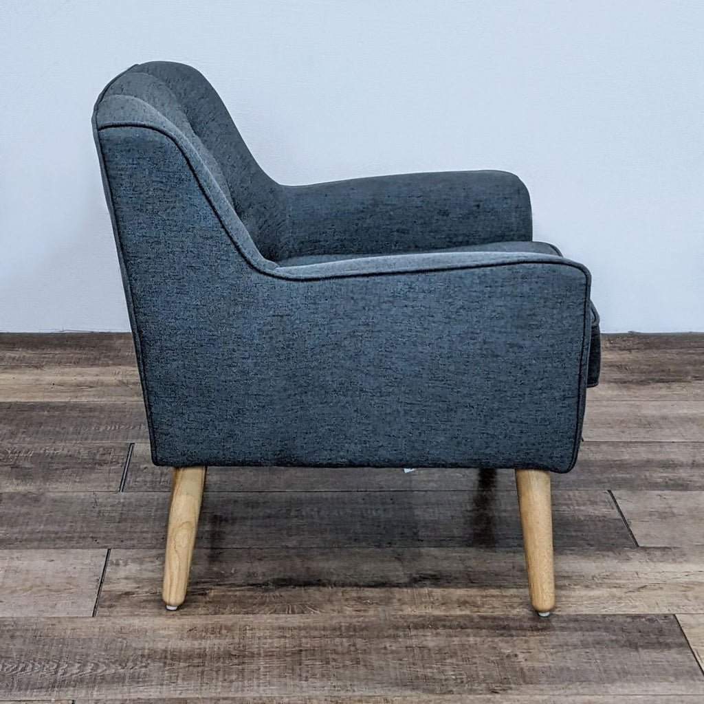 Side view of a dark fabric mid-century armchair with wooden legs, showcasing sleek lines.