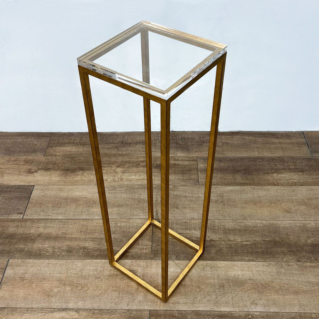 Rectangular stand with gold frame and glass top, ideal for display purposes, on wooden flooring.
