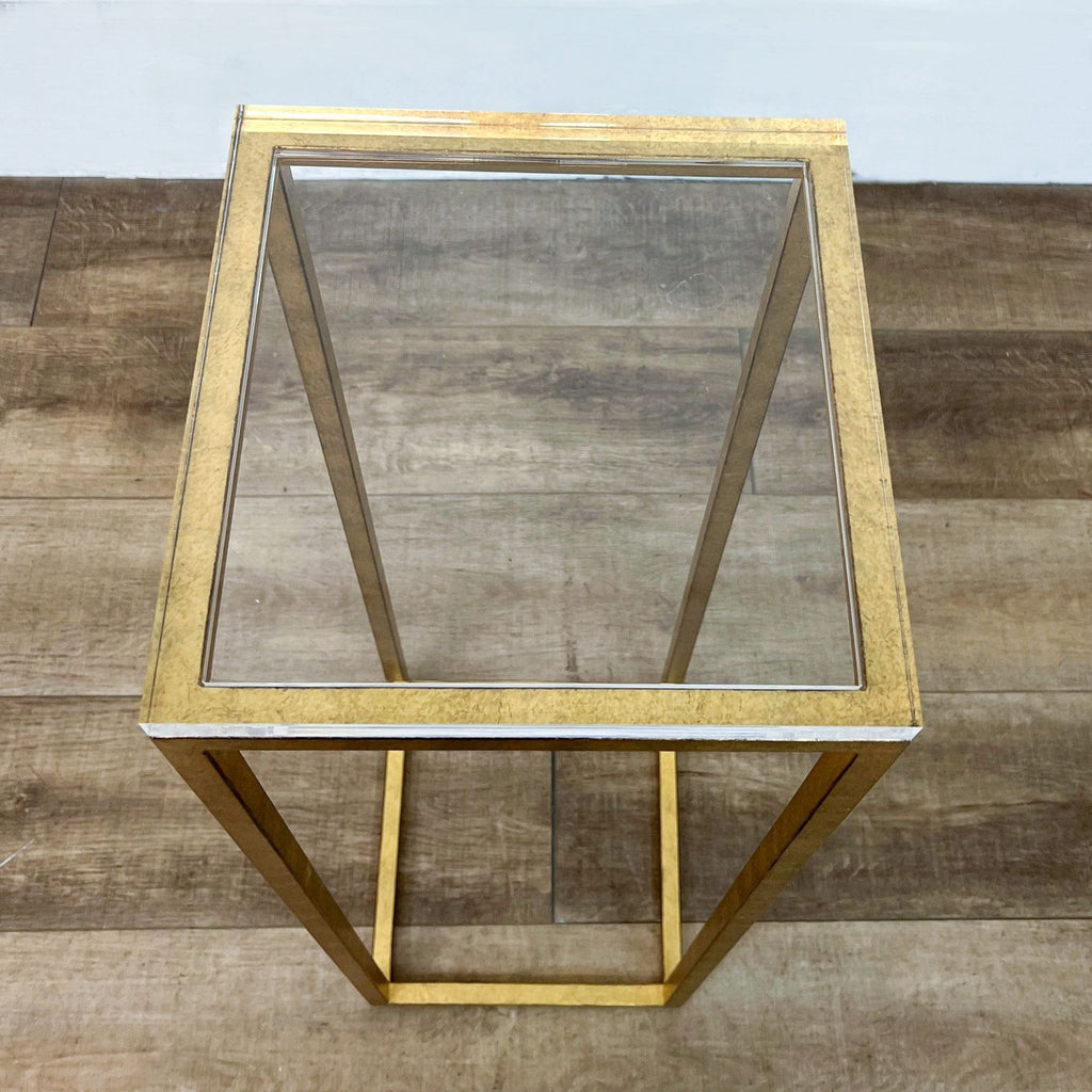 Gold metal stand with transparent top, showcasing modern minimalistic design on wooden surface.
