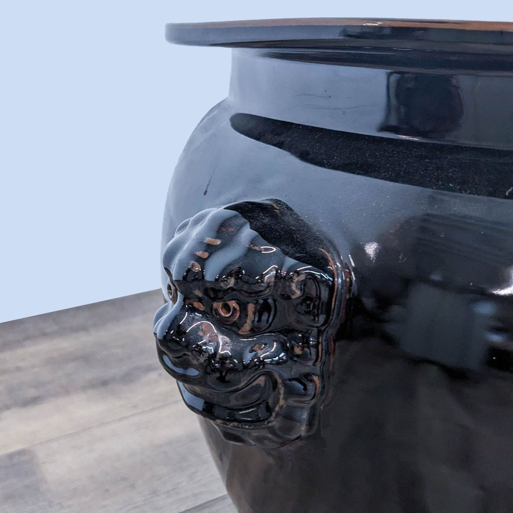 Close-up of a lion motif on a black Reperch vase.
