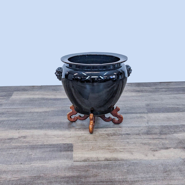 Black Reperch vase on a decorative wooden stand.