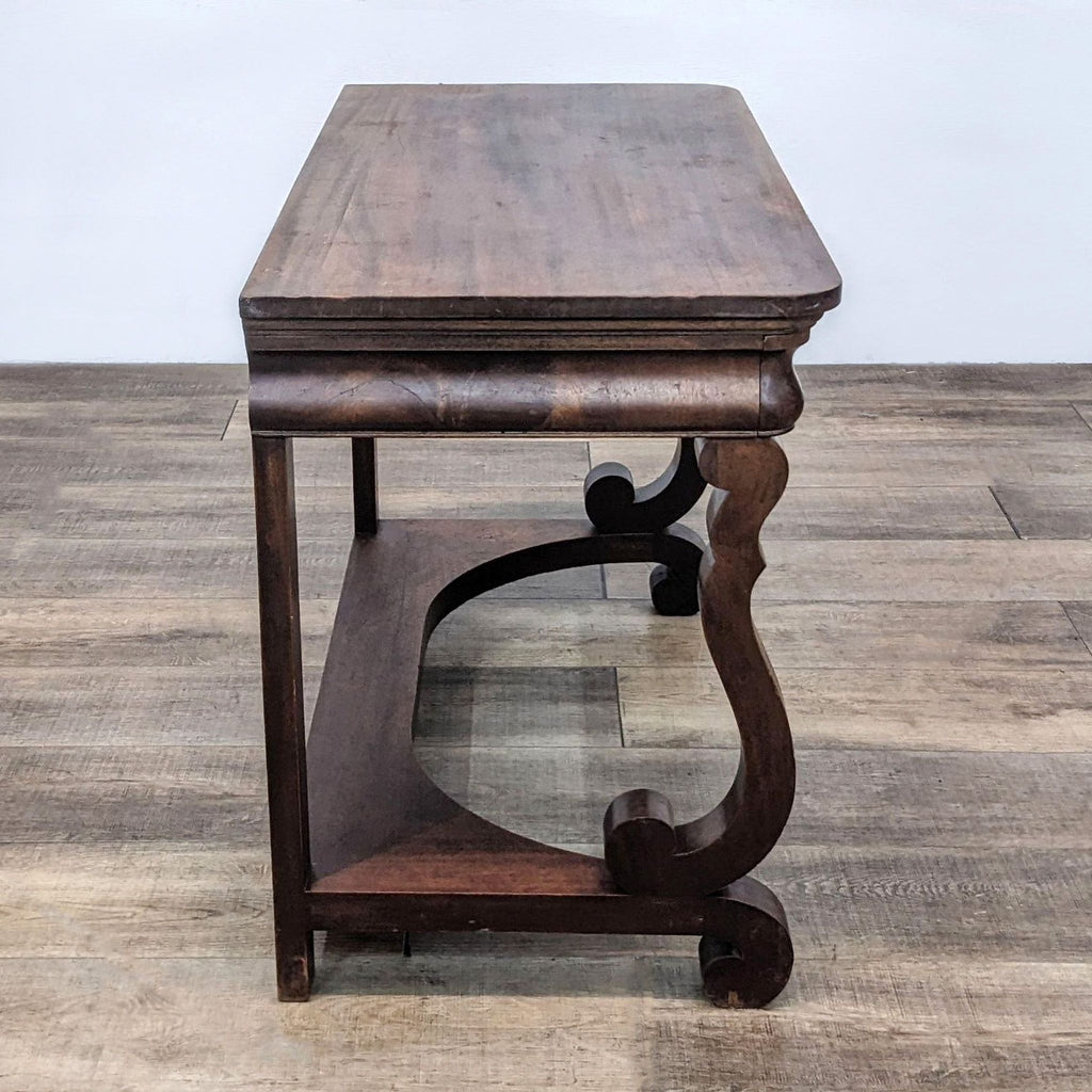 Side view of mahogany desk with elegant curves and grain.