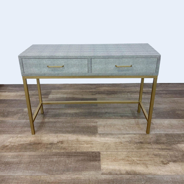 Gray console table with gold metal base and two closed drawers.
