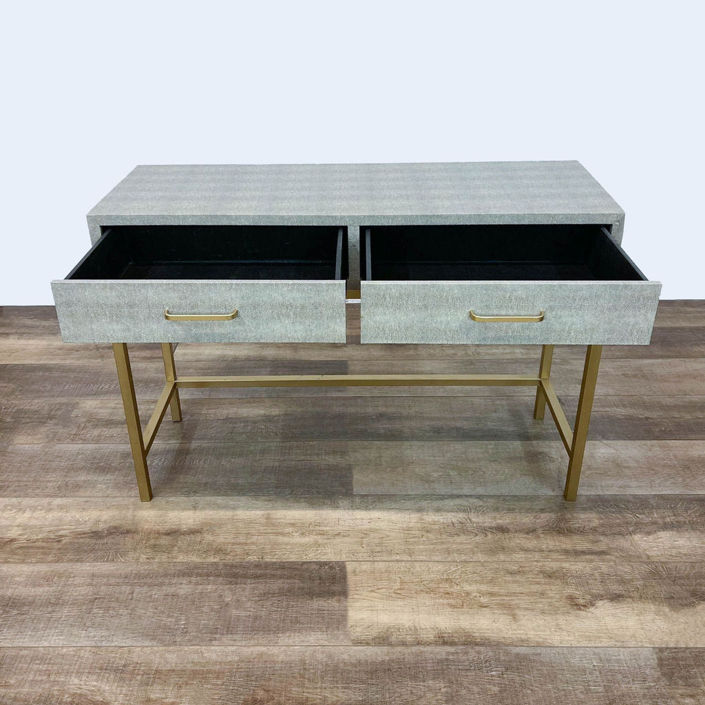 Console table with gray top, gold base, and open drawers.