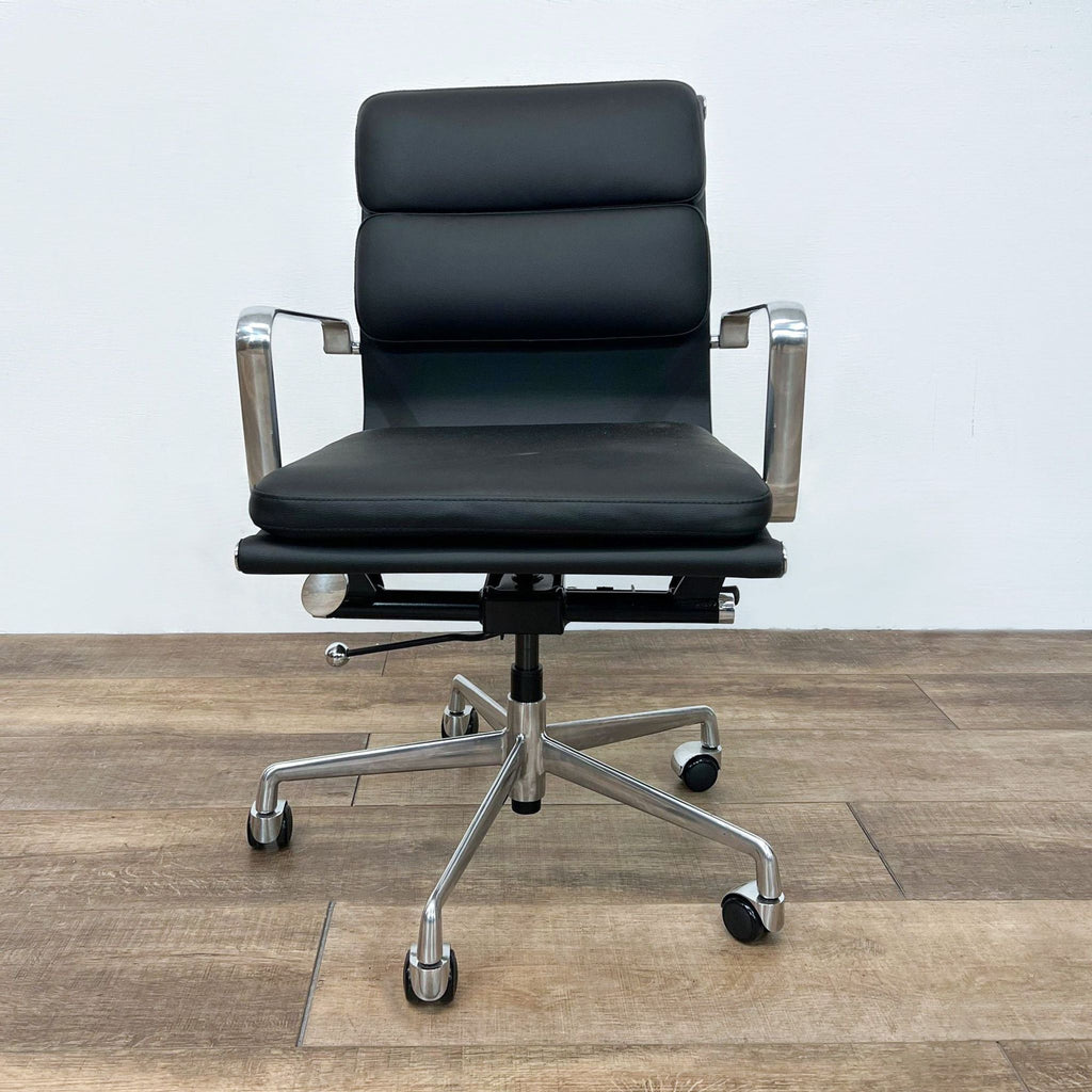 Modern black office chair with padded vegan leather and aluminum frame, on a wooden floor.