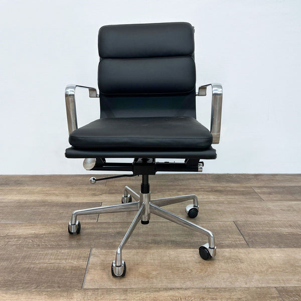 Modern black office chair with padded vegan leather and aluminum frame, on a wooden floor.