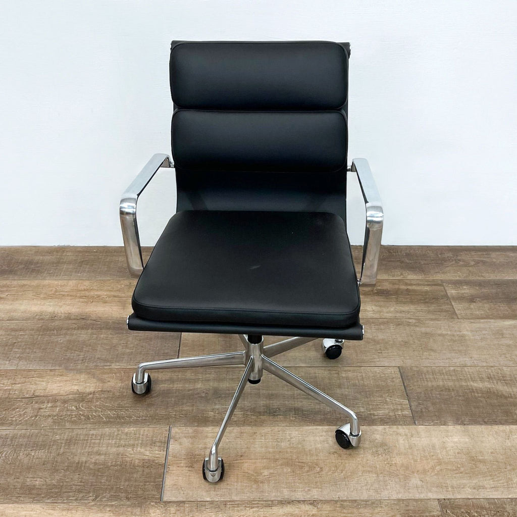 Front view of a black, vegan leather chair featuring a sturdy aluminum frame and caster wheels.