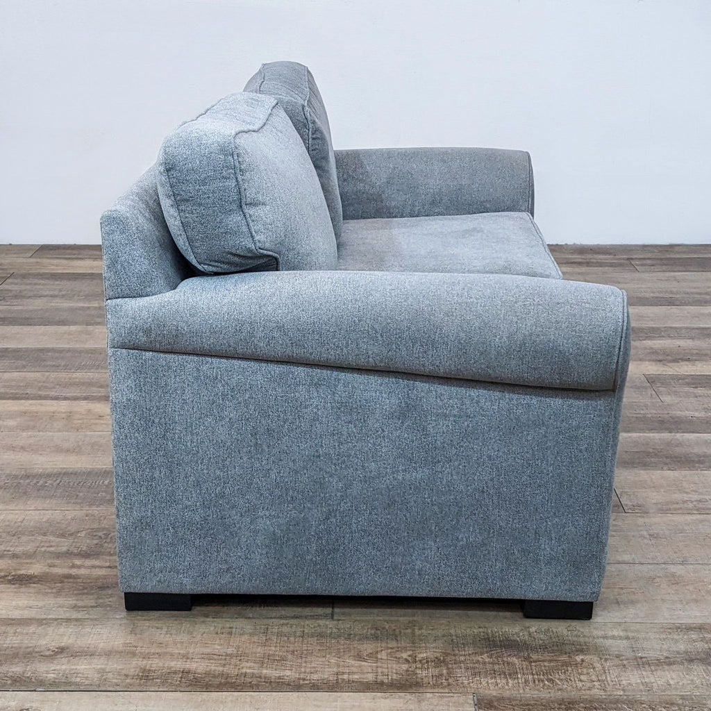 Side view of gray loveseat showing rolled arm and cushion detail.