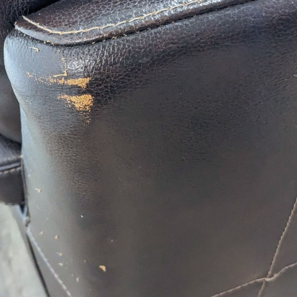 Close-up of worn leather on the edge of the Reperch sectional, showing slight damage to the material.