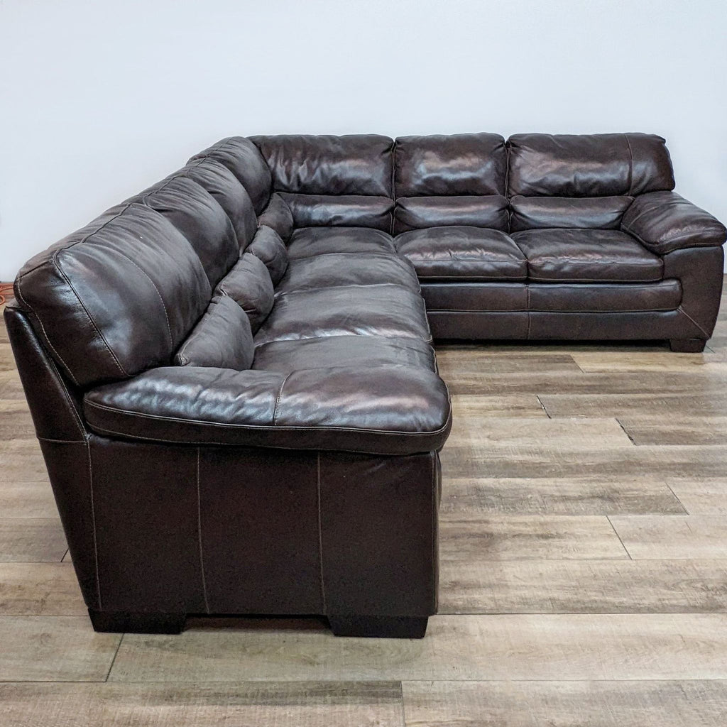Large brown leather sectional with high back and pillow top arms, arranged in an L-shape.