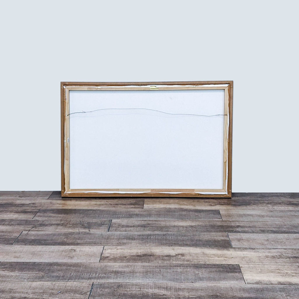 Backside of a framed canvas print showing wiring for hanging. Wooden frame visible.