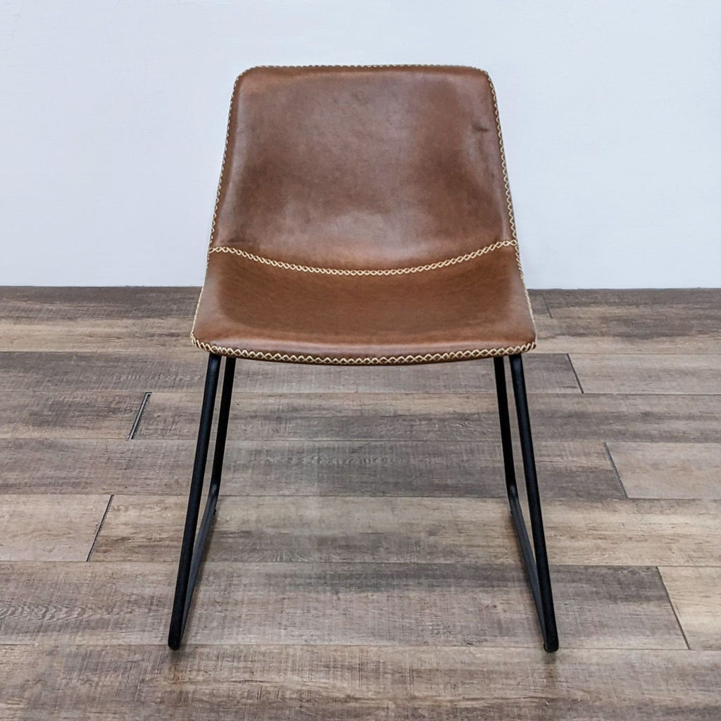 Front view of a brown faux leather dining chair with a bucket seat and metal legs.