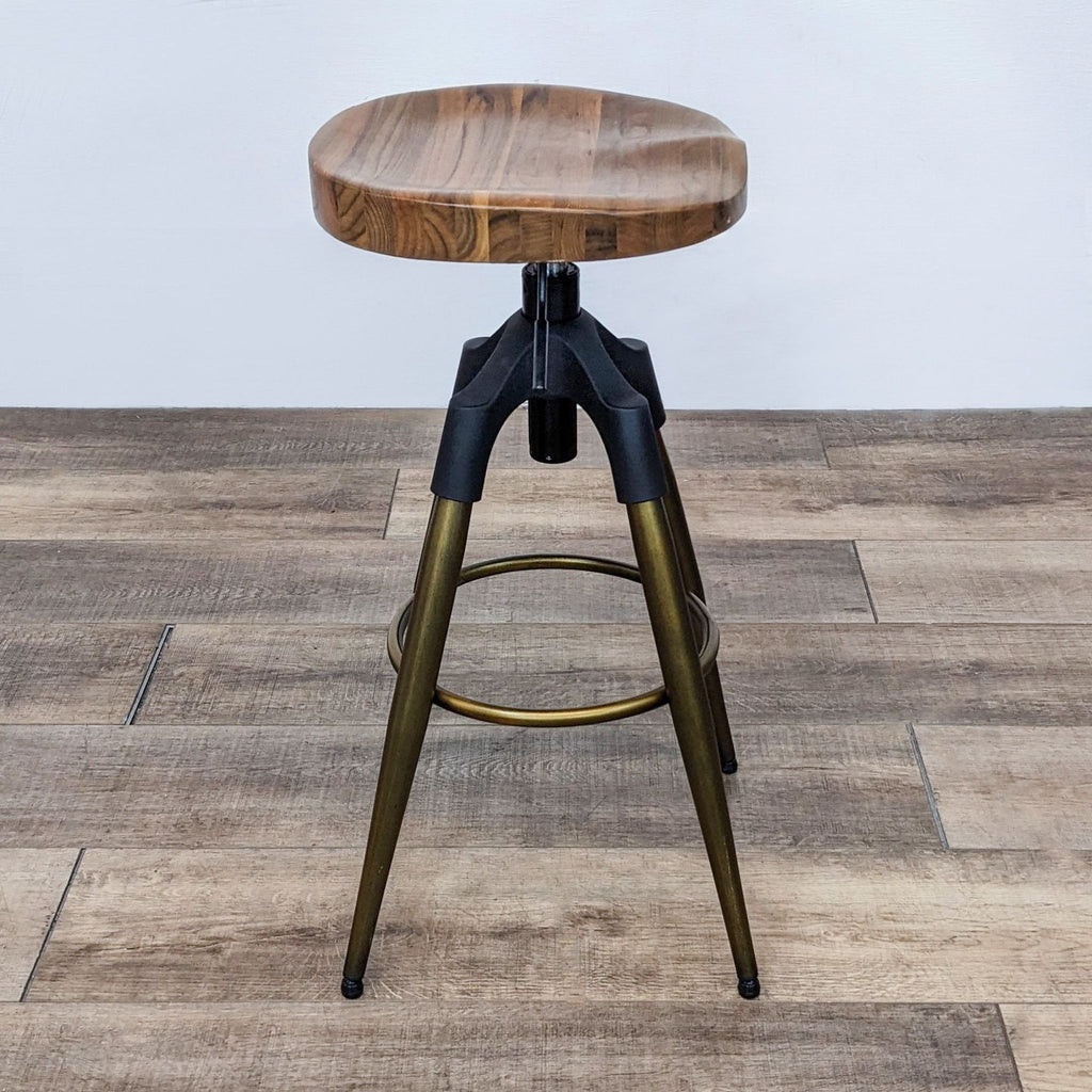 Side view of the stool with wood round seat, gold and black legs, adjustable height mechanism.  