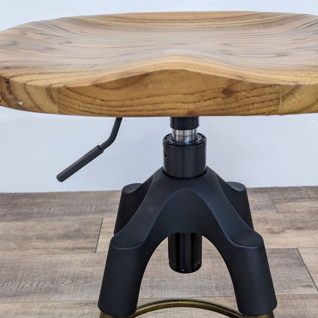 Close-up of round wooden seat with natural grain, black adjustable frame below.  