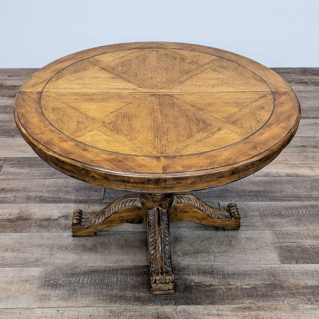 Top view of a round wooden dining table with decorative pedestal base.