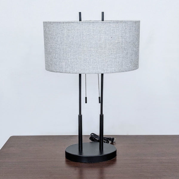 Modern table lamp with black base and dual light bulbs under a gray fabric shade.