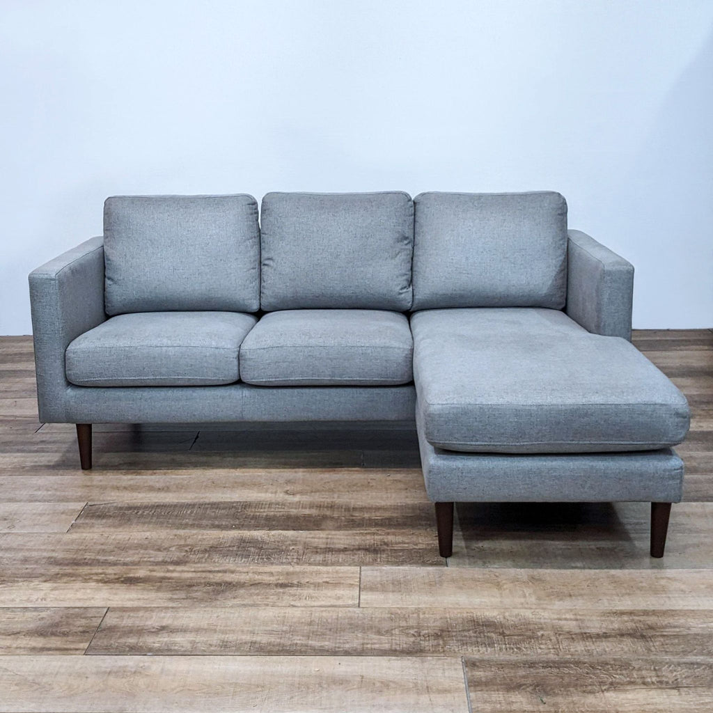 Gray fabric sectional with reversible chaise, narrow arms, and tapered wood feet.