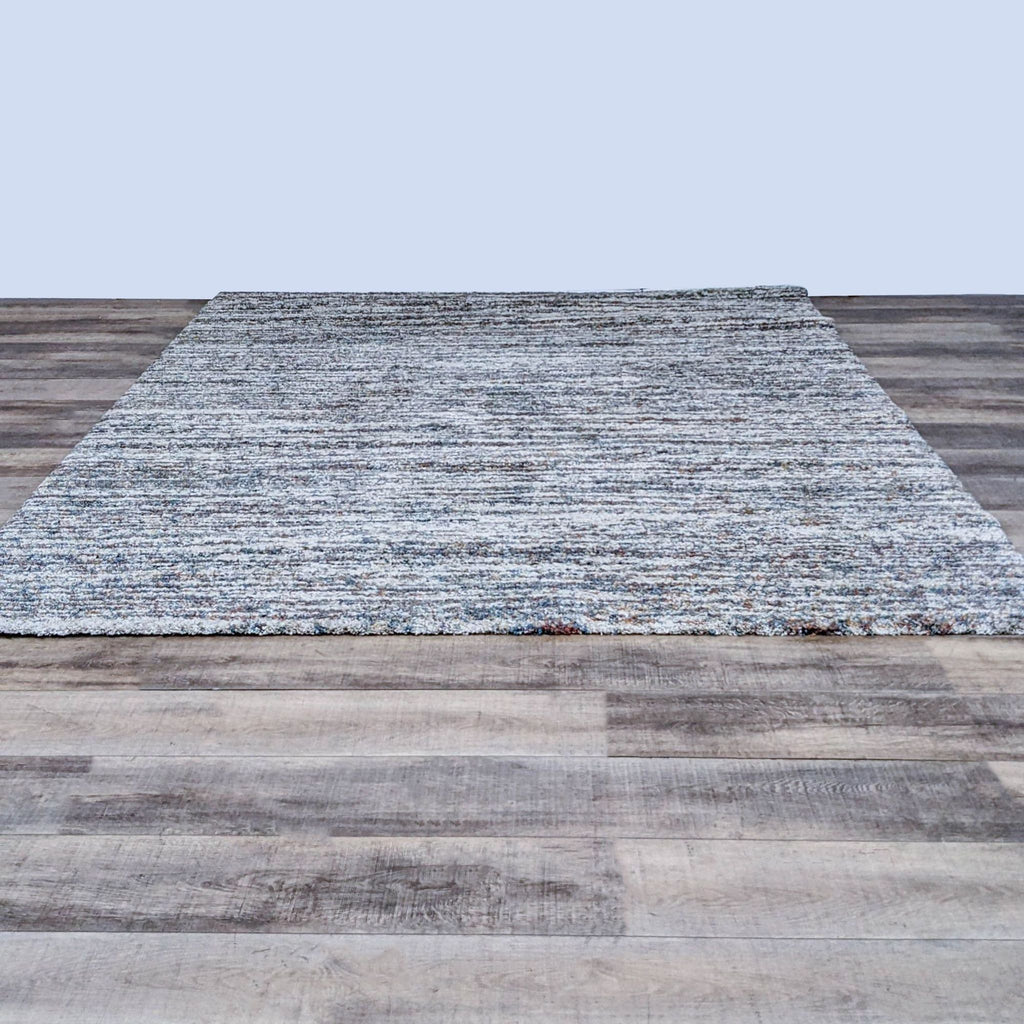 Granada Ezra Area Rug with earth tones, ivory, blue, orange, and rust on a hardwood floor.