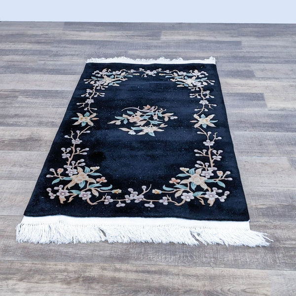 Floral Oriental area rug with a black background and intricate floral design, featuring fringe on edges.