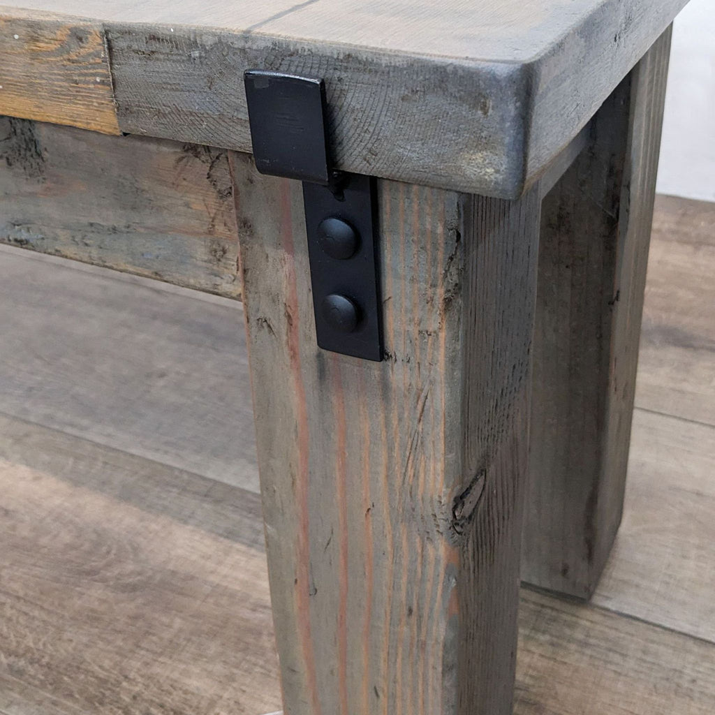 3. Close-up of black metal hardware detail on a solid wood bench leg, showing handcrafted texture.
