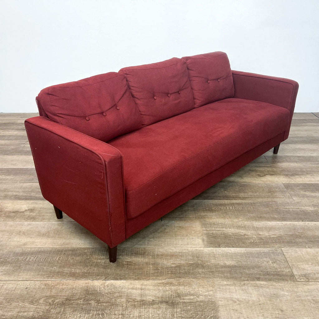 Three-seat red sofa, tufted cushions, narrow arms, wooden feet.