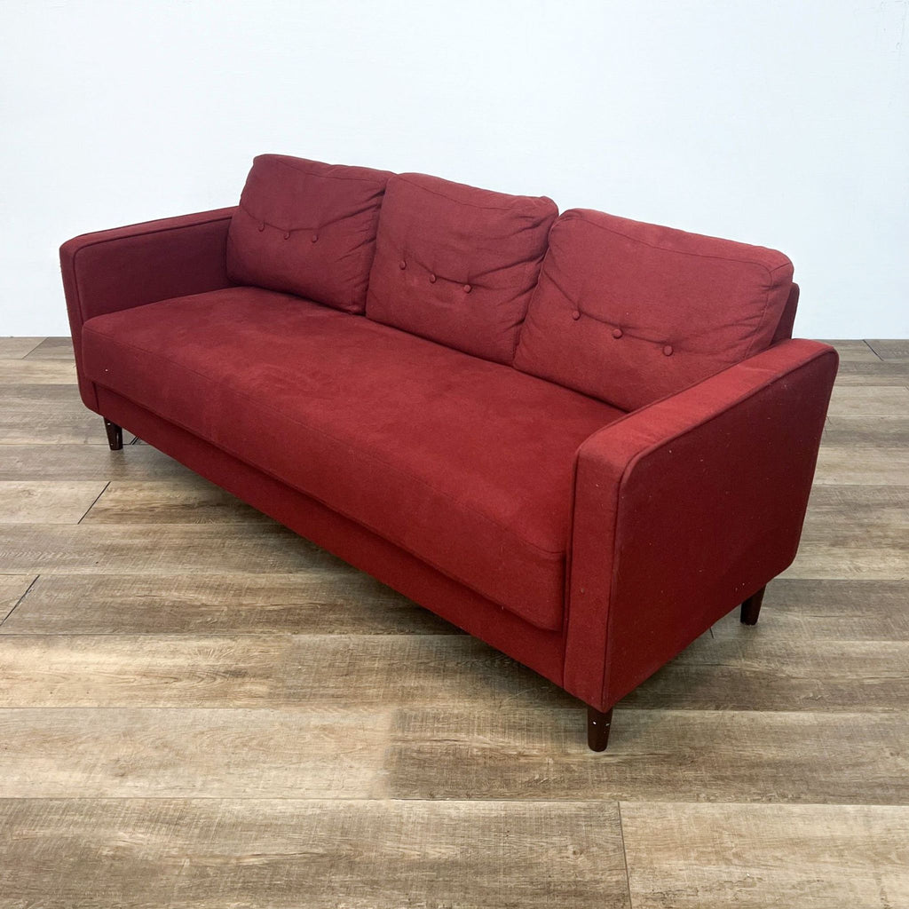 Compact red 3-seat sofa with tufted cushions, narrow arms, tapered wood legs.