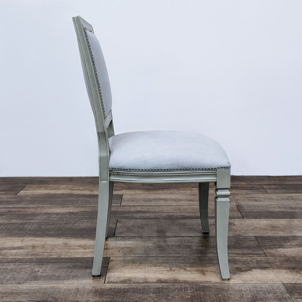 Side view of a vintage dining chair, showing its upholstered seat and elegant wood design.