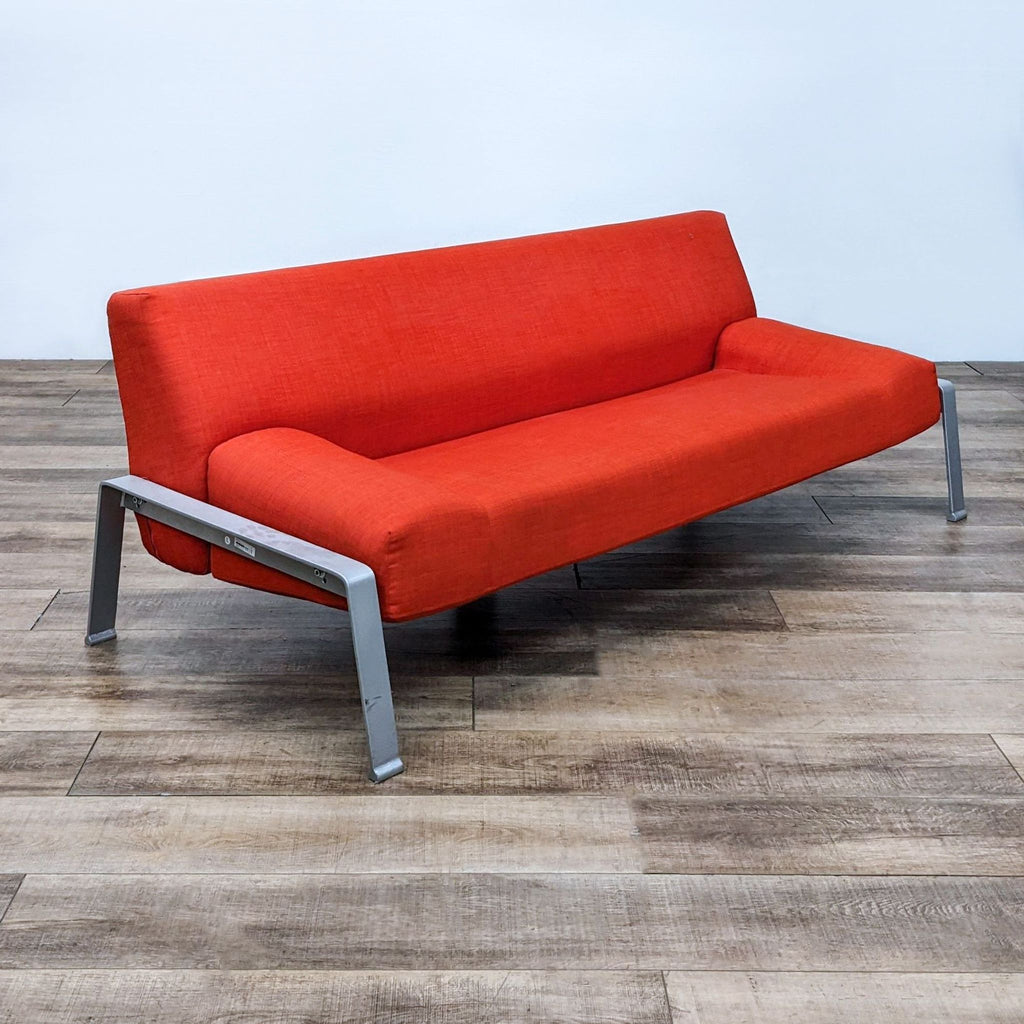 Angled view of a modern red compact 3-seat sofa with a sturdy metal frame.