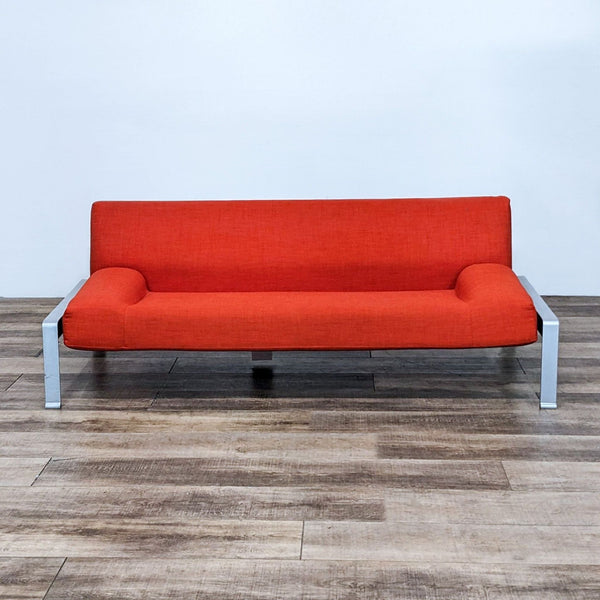 Modern red 3-seat sofa with low arms and a metal frame on wooden flooring.