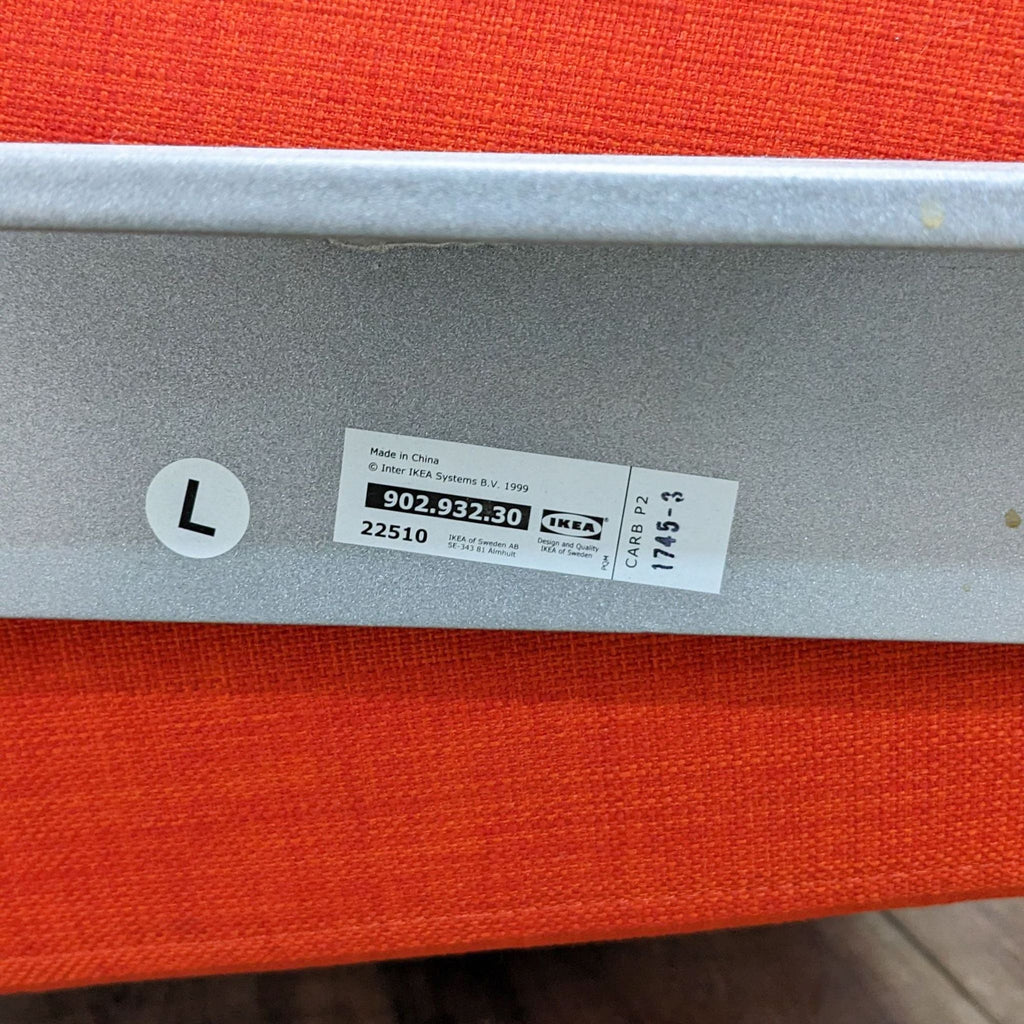 Close-up of an Ikea label on a red fabric with a metallic frame in the background.