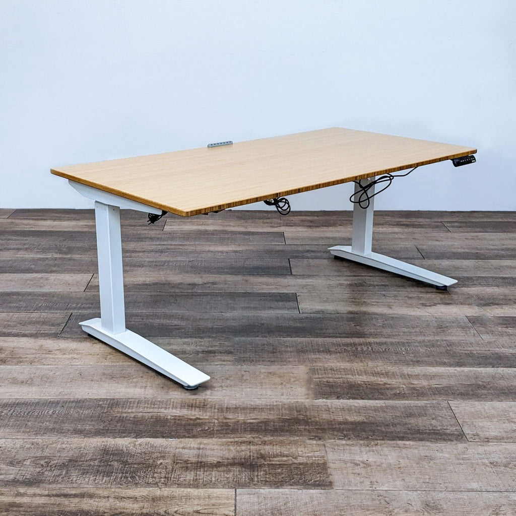 Jarvis Bamboo Top Desk with white frame and motorized height adjustment on wooden floor.