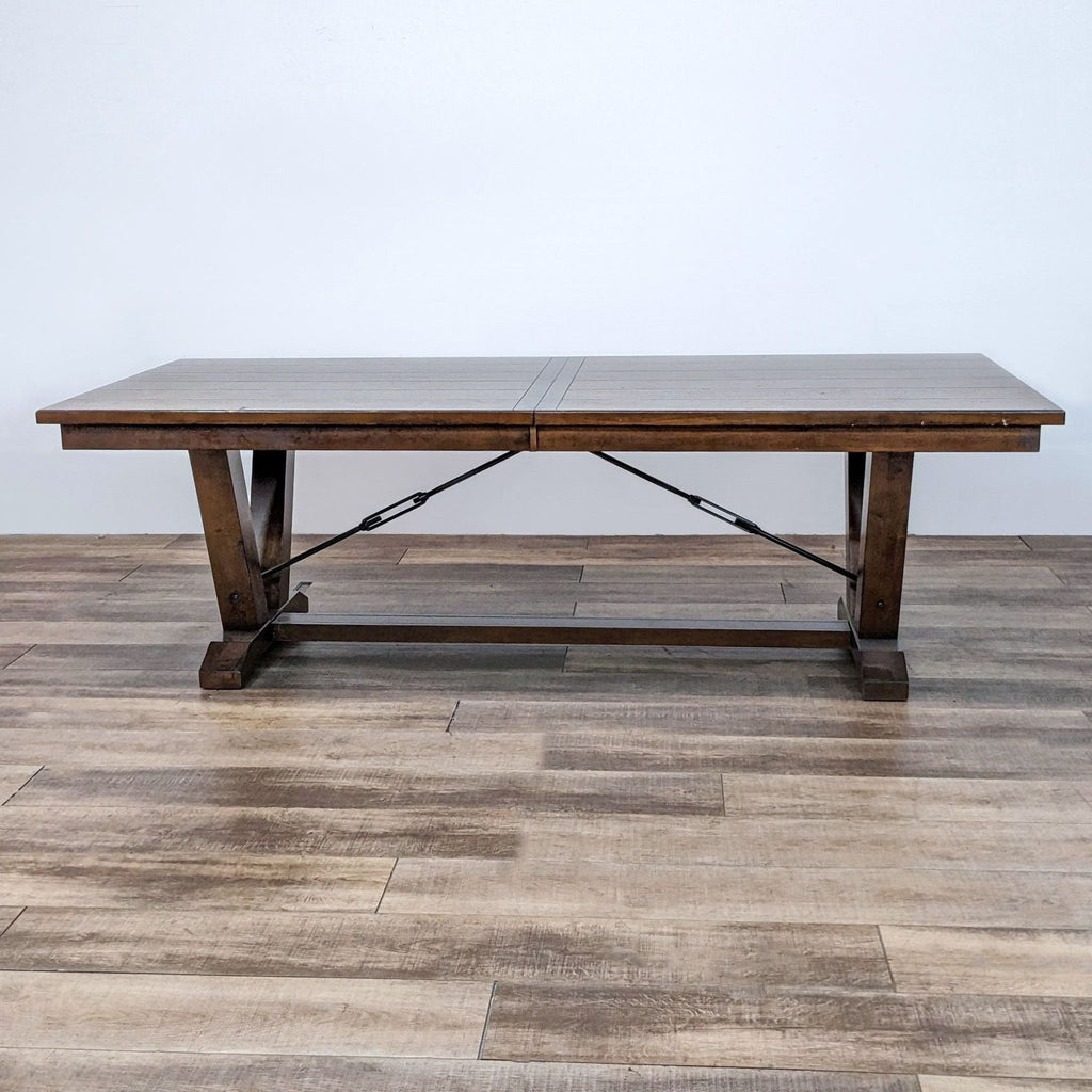Dining table with a trestle base and metal accents, part of the Bayside Furnishings collection.  