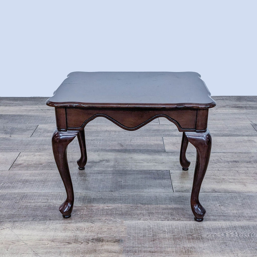 Elegant end table by Reperch with carved design and curved legs.