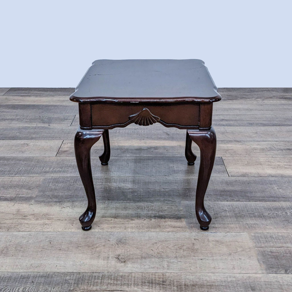 Wooden end table featuring scalloped apron and cabriole legs.