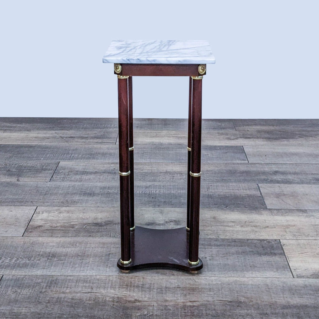 Reperch end table with brass embellishments and a marble top on wooden legs.