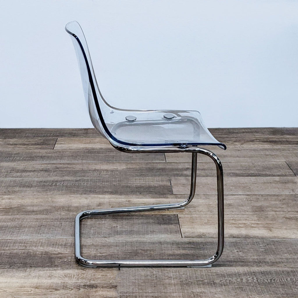 Side view of a transparent IKEA dining chair with chrome base.