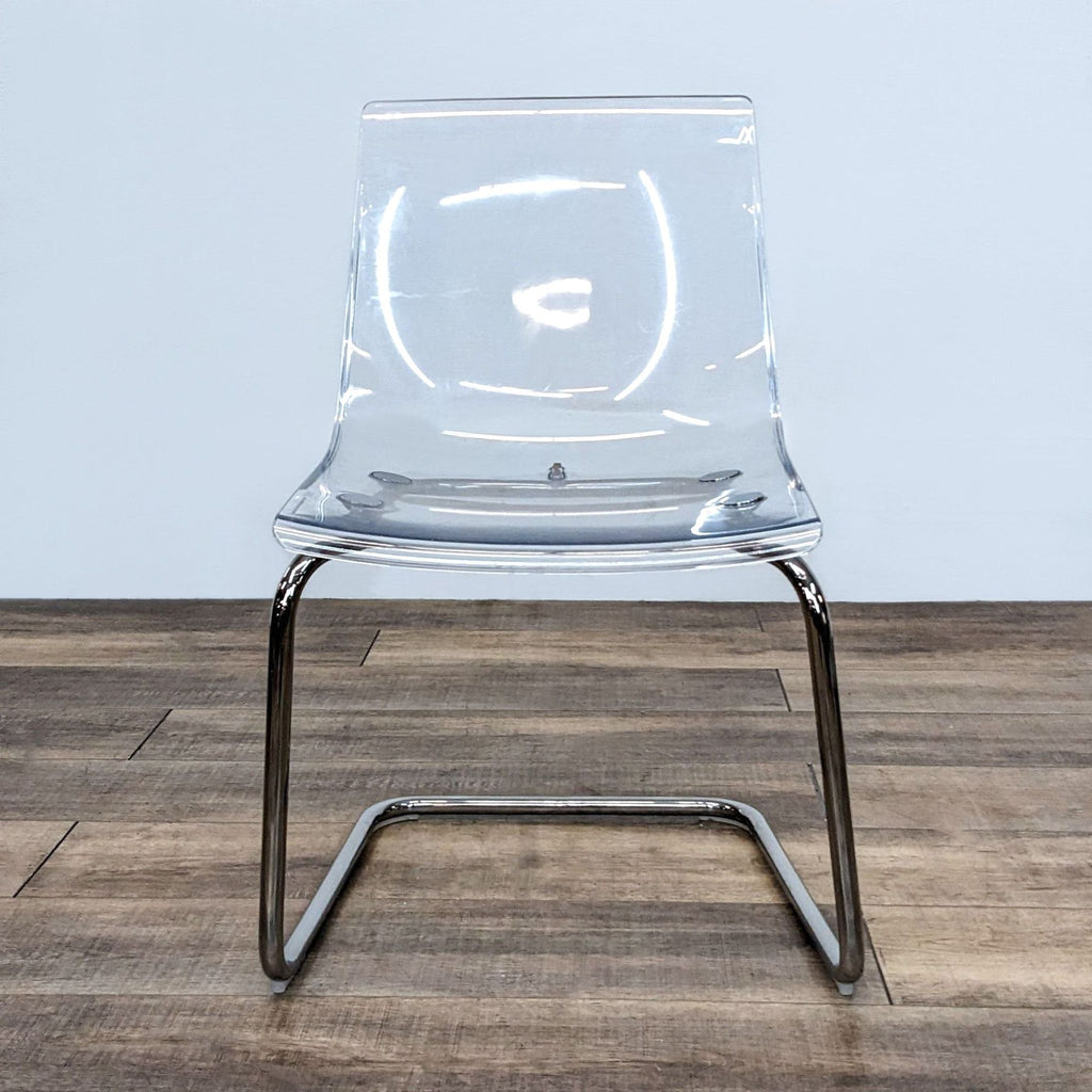 Transparent IKEA dining chair with a flexible seat and chrome-plated base.
