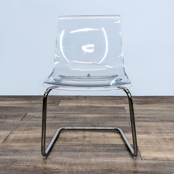 Transparent IKEA dining chair with a flexible seat and chrome-plated base.